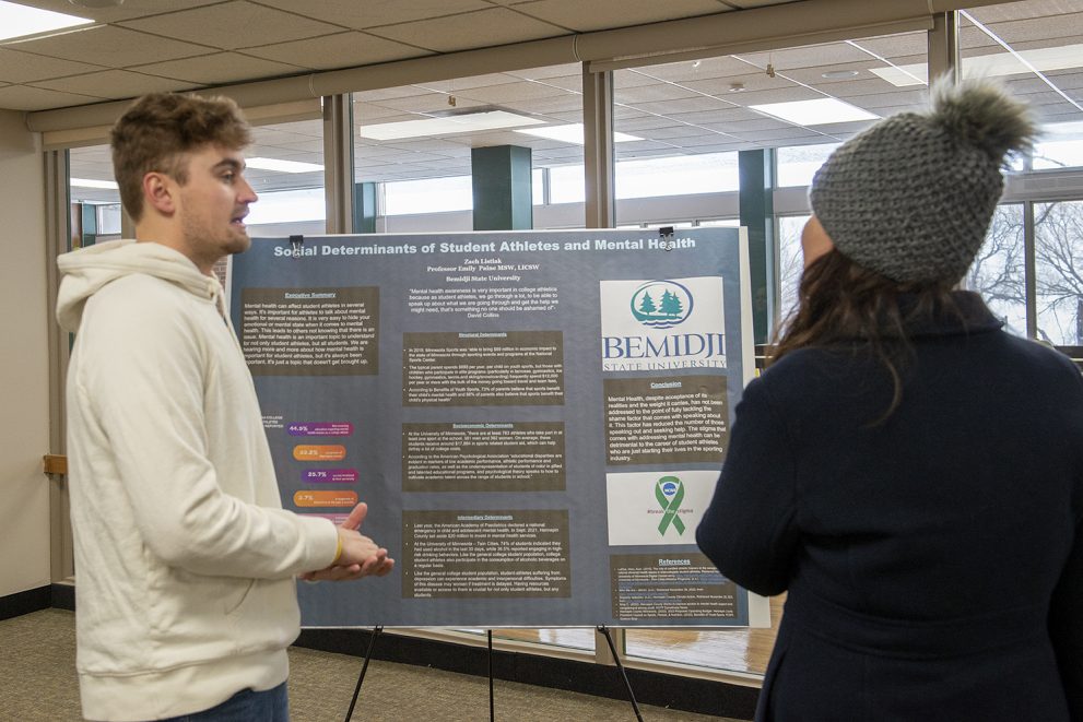 A student presenting a poster: Social Determinants of Student Athletes and Mental Health
