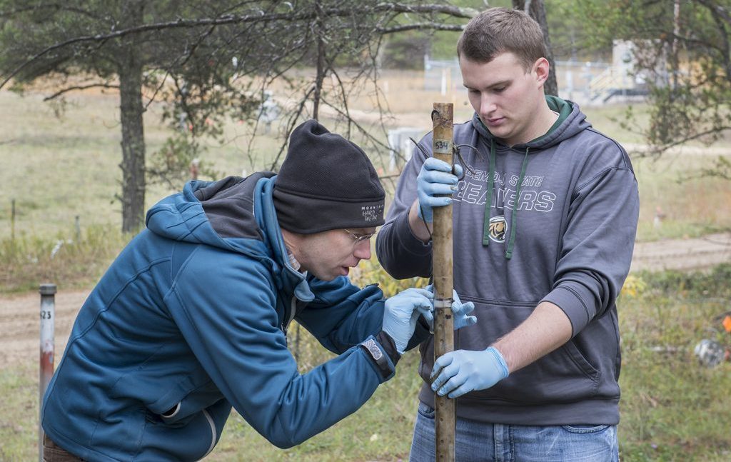 Dr Carl Isaacson measuring a stick with a student in the field
