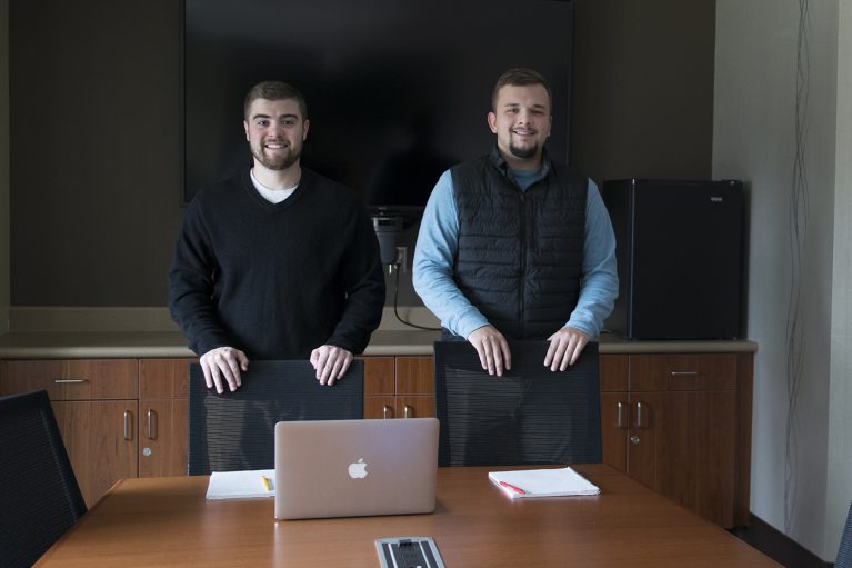 Two students standing around a desk