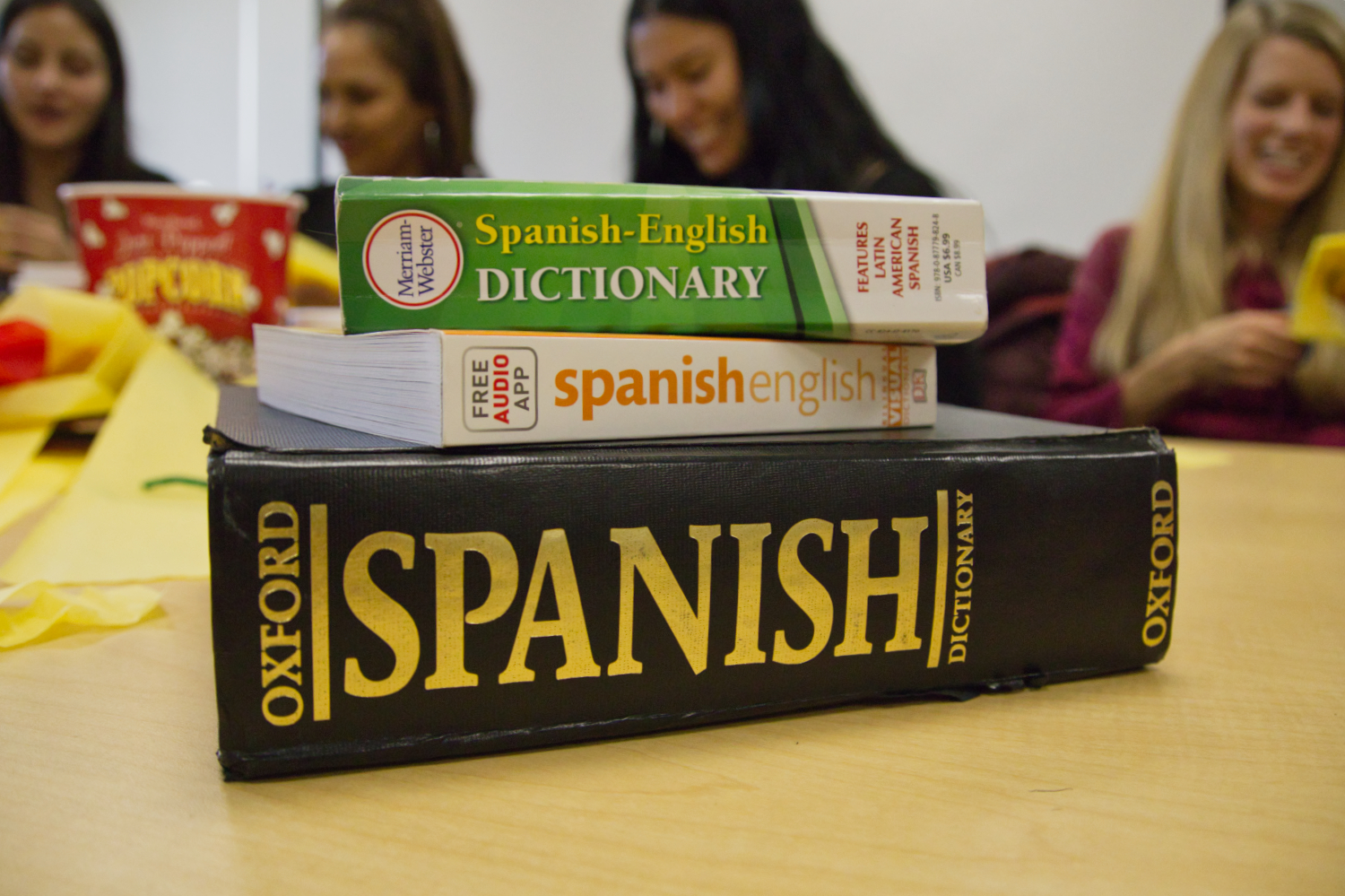 Spanish dictionaries stacked on top of one another, with students in the background