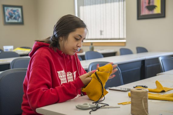 A student making a moccasin during Ojibwe camp in 2019