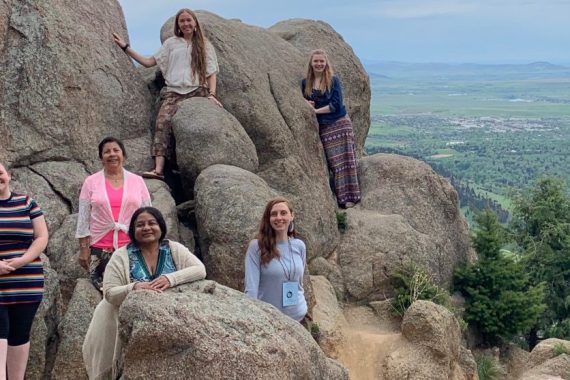 Students standing around a large rock formation overlooking a valley