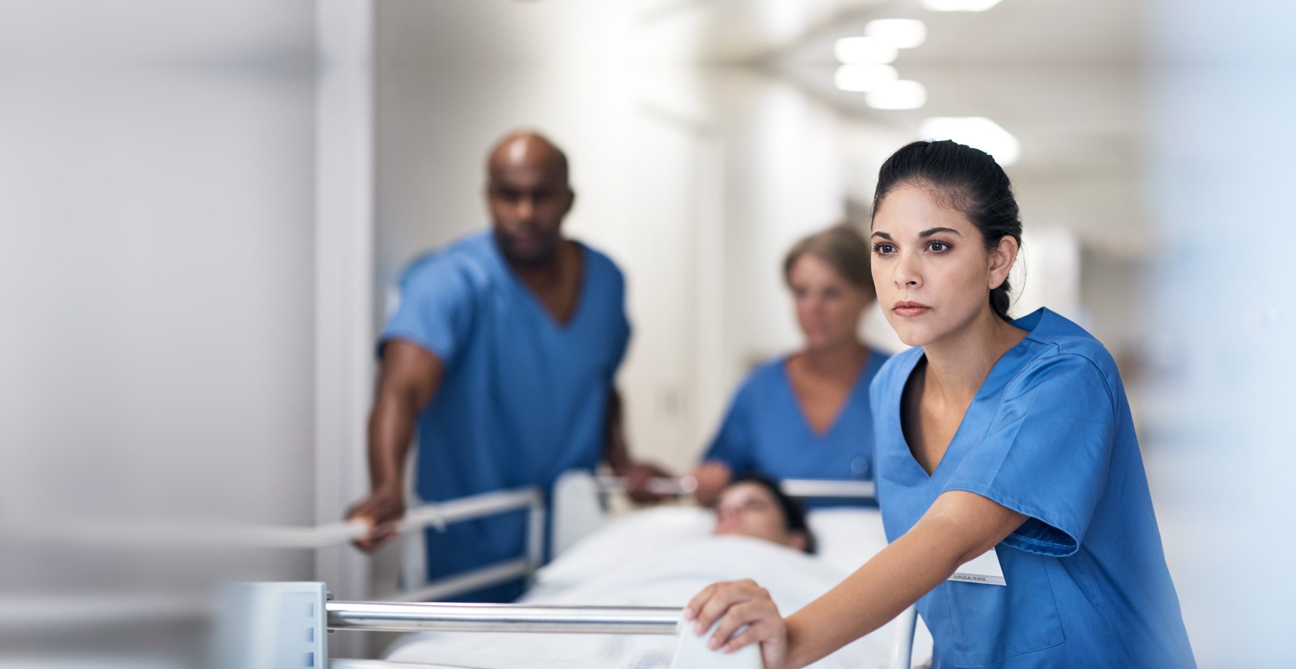 Nursing pushing a hospital bed down a hospital hallway