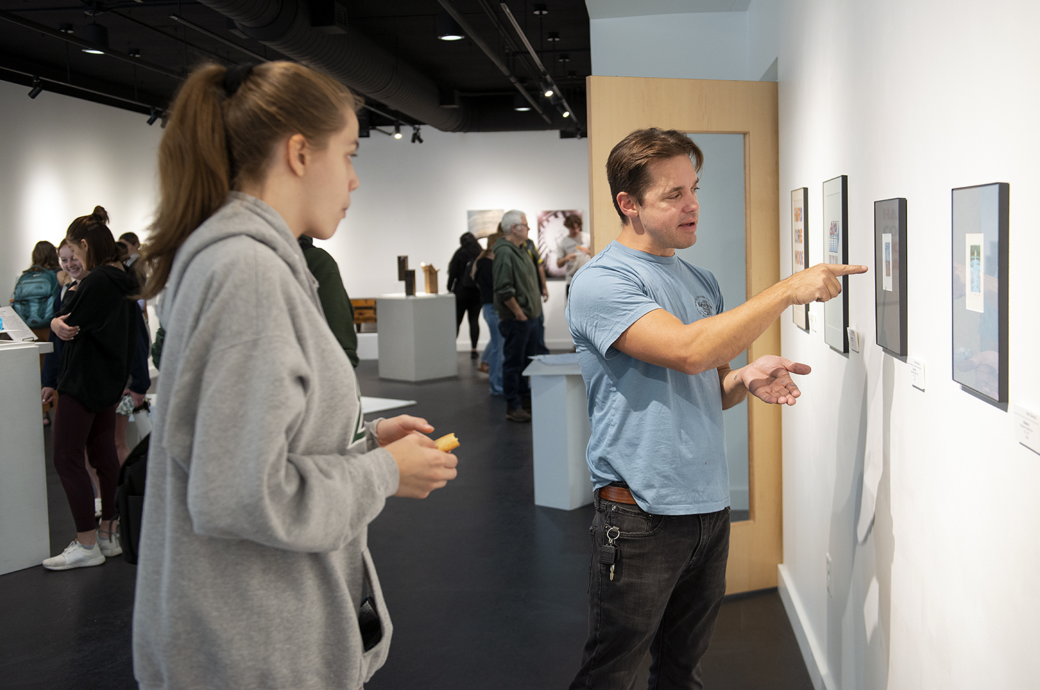 BSU faculty member pointing to art in a gallery and speaking with a student
