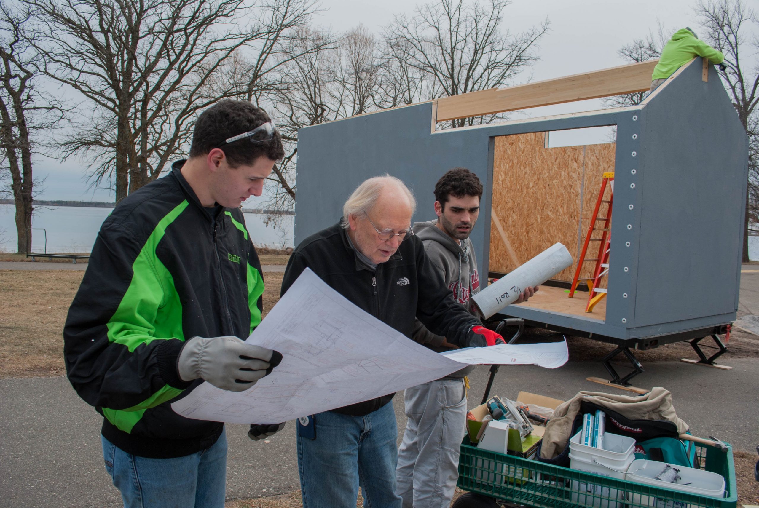 Students looking over plans for a tiny house project with a faculty advisor