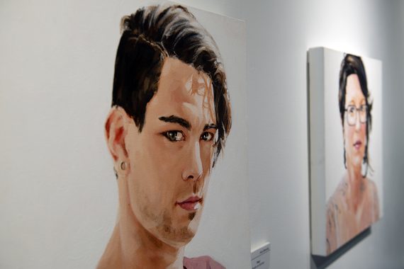 Two paintings, one of a man, his gaze directed toward the camera and the other of a woman