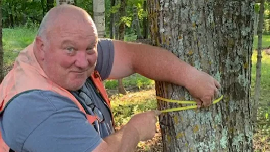 Jim measuring the distance around a tree.