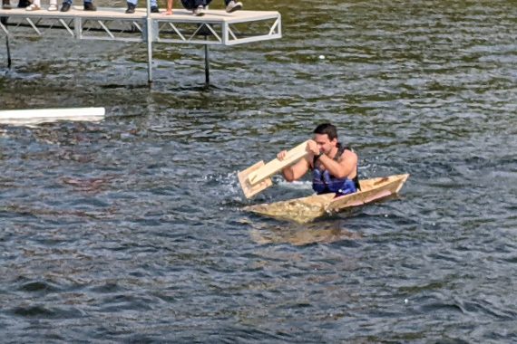 Evan Rabe paddles furiously to stay afloat. plywood kayak takes on water during boat race