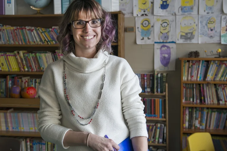 a woman in a classroom with books in the background