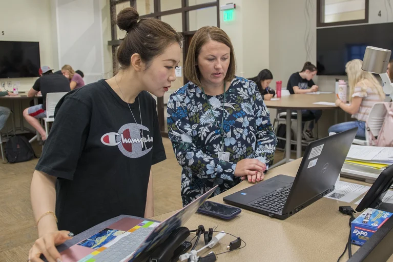 a professor showing a student something on a laptop