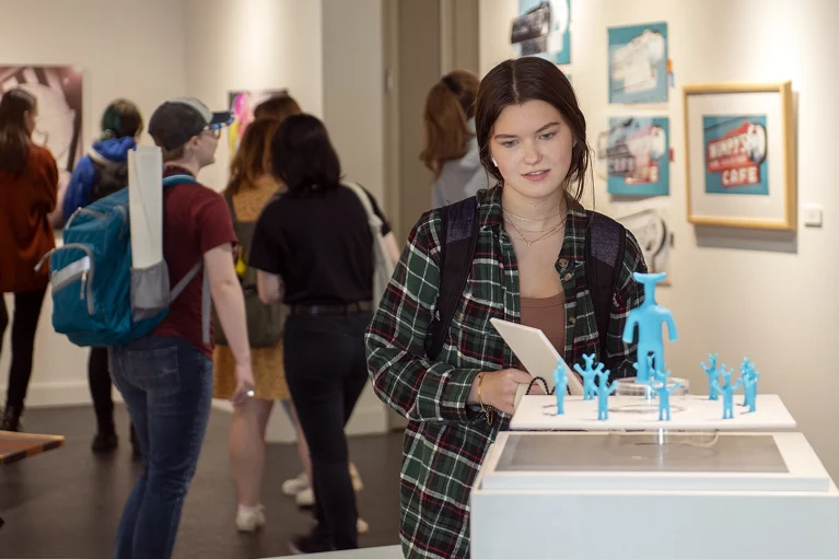 A student looking at a 3-d display in a gallery