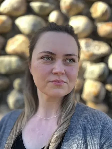 Headshot of Maggie in front of a stone wall.