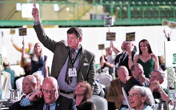 Multiple people hold up bidding signs