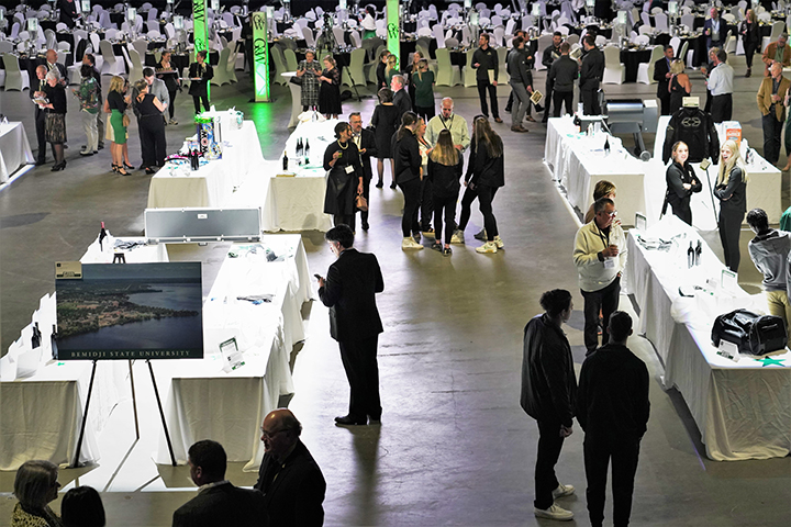 A crowd of people examining bidding items on various tables