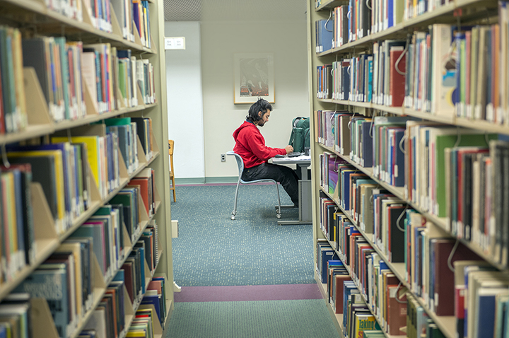 A student sitting at a desk in a library