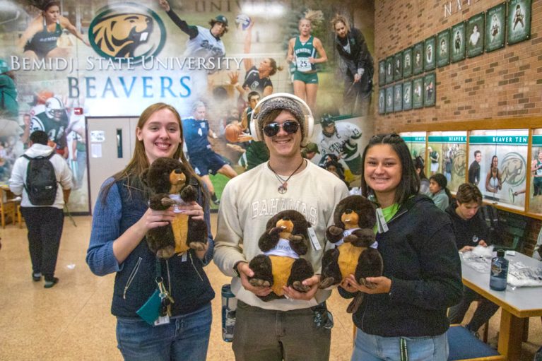Students holding stuffed beavers at camera