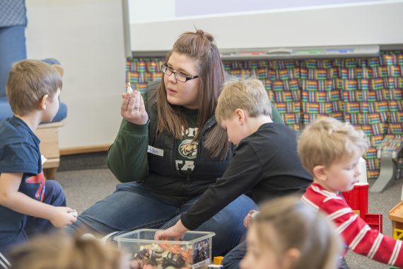 A student teacher showing young students a figure in a classroom