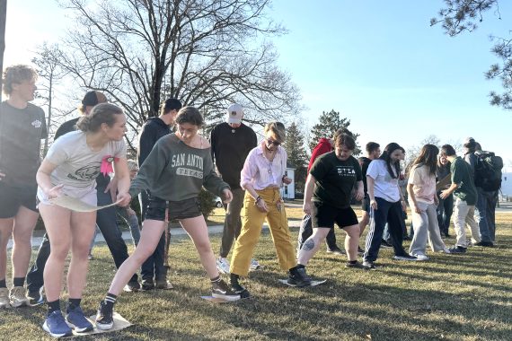 Students standing in a line and talking to each other as they play a game.