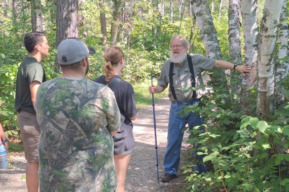 Students listen to Dr. Fulton as they learn about trees on hiking path.