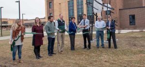 President Faith Hensrud (fourth from right) joins sculptor Jon Kamrath in a ribbon-cutting for his "Northscape" sculptures Dec. 1 outside Memorial Hall.