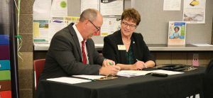 President Faith Hensrud signs transfer agreements with Anoka Technical College President Dr. Kent Hanson Oct. 10 in Anoka.