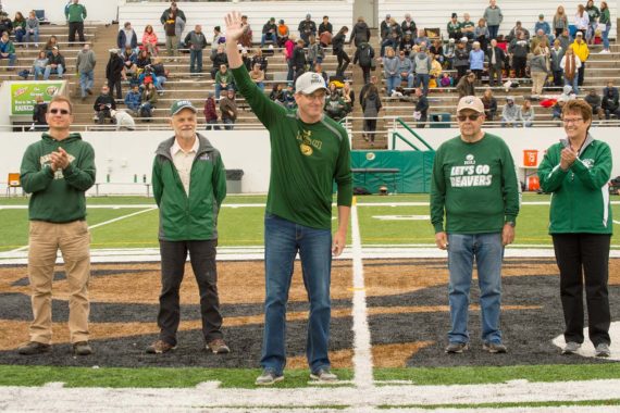 Outstanding Alumni honorees Jason Edens &rsquo;07 (left), Dr. Dale Greenwalt &rsquo;75, Brian Maciej &rsquo;86 and Dr. Gene Ness &rsquo;66 are recognized at halftime with President Faith Hensrud on Sept. 23.