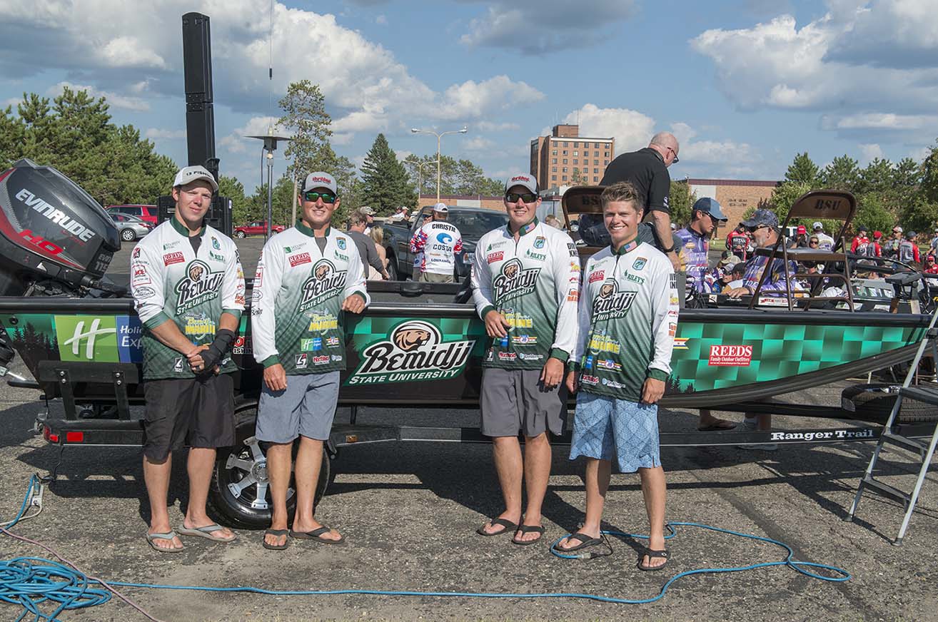 The two qualifying teams for Bemidji State, Mitch (left) and Thor Swanson and Luke Gilland and Robby Troje, pose with the team boat at an Aug. 7 Meet the Teams event at Bemidji State.
