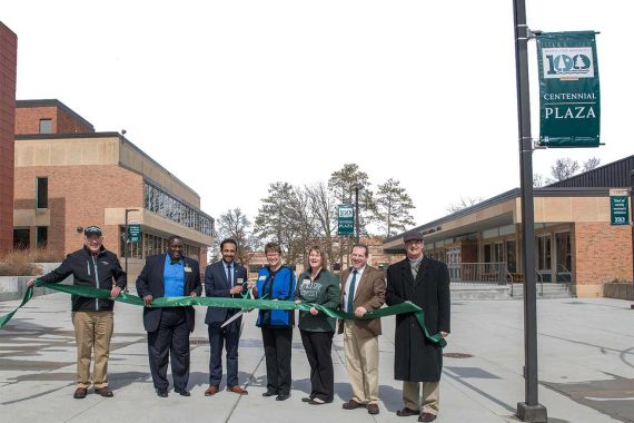 President Faith Hensrud, center, prepares to cut the ribbon for dedication of the newly renamed Centennial Plaza on April 12. She is joined by, from left, President Emeritus Jim Bensen, Associate Vice President for Student Life & Success Jesse Grant, outgoing Student Senate President Ash Ullah, Hobson Memorial Union Director Nina Johnson, Executive Director of Communications & Marketing Scott Faust and President Emeritus Jon Quistgaard.