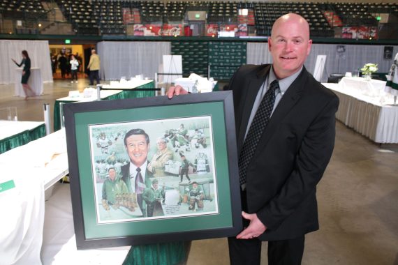 Vince Huerd poses with a commemorative print of his former coach, Bob Peters.