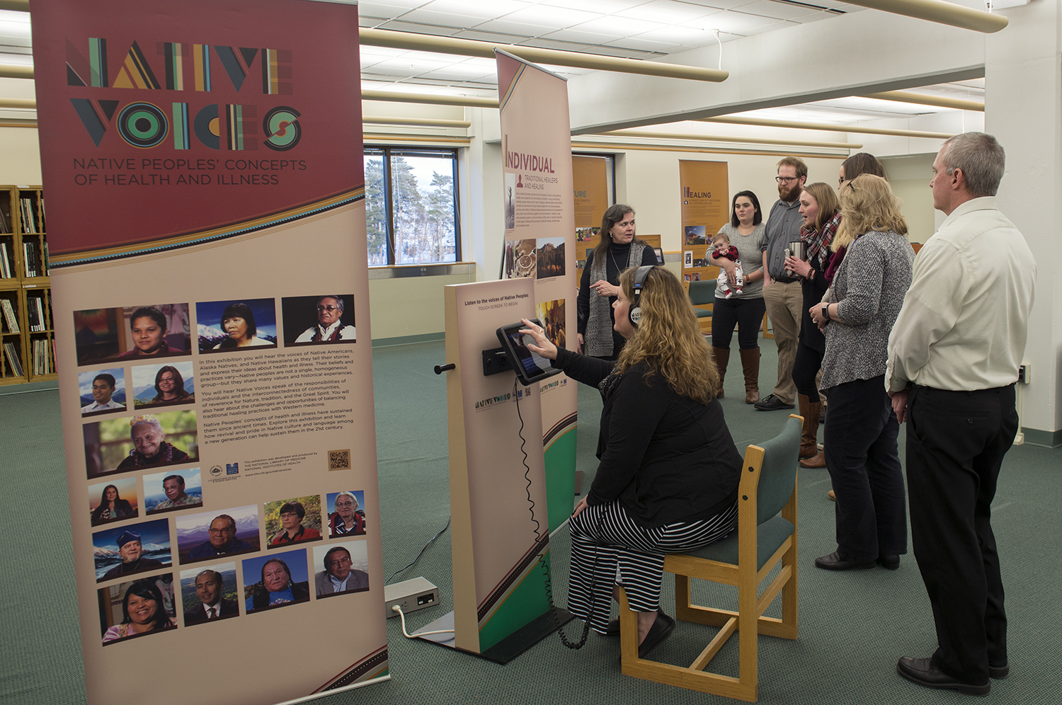 Bemidji State University faculty and staff viewing the Native Voices concept banners and using the installed iPads that feature video testimonials.