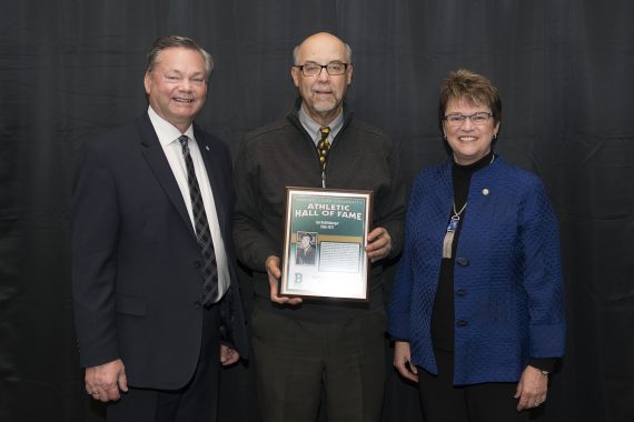 Tracy Dill, director of athletics, and President Faith Hensrud pictured with Len Rolisberger.
