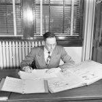 A black and white photo of Dr. Harold Hagg reading several documents at a desk