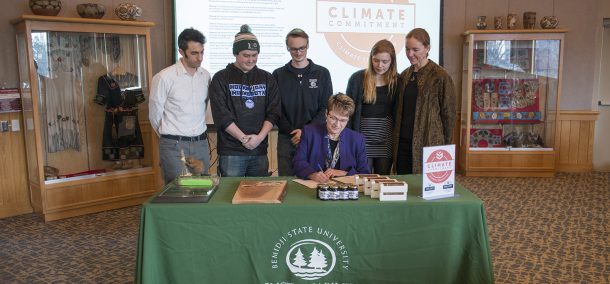 President Faith Hensrud signs Second Nature's Climate Commitment