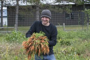 Sustainability office student with carrots from the campus garden.