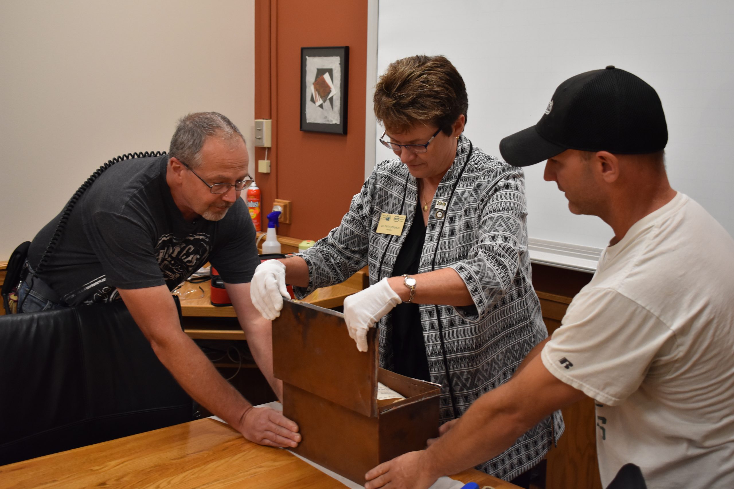 BSU President Faith Hensrud opens BSU's 1918 time capsule on Sept. 19,2019, with help from Brian Ingalls and Mitch Bannor from the BSU Buildings and Grounds staff.