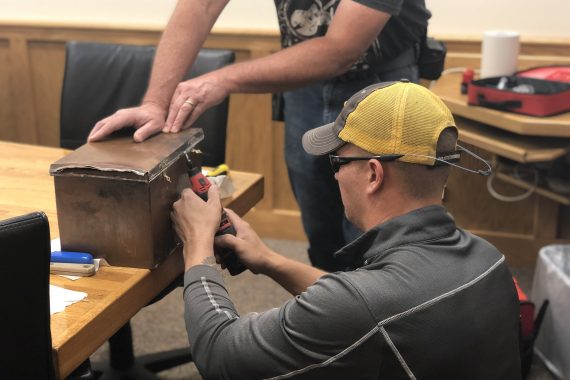 Brett Steinmetz from the BSU facilities staff uses a powered saw to cut open the time capsule.
