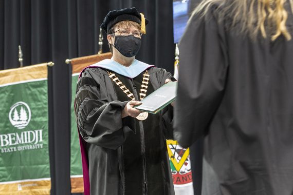 President Faith C. Hensrud confers a diploma