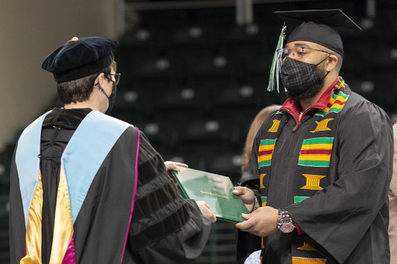 President Faith C. Hensrud confers a diploma