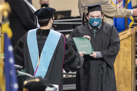 President Faith C. Hensrud confers a diploma