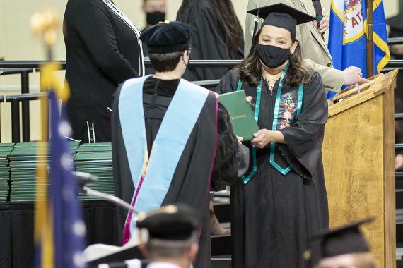 President Faith C. Hensrud confers a diploma