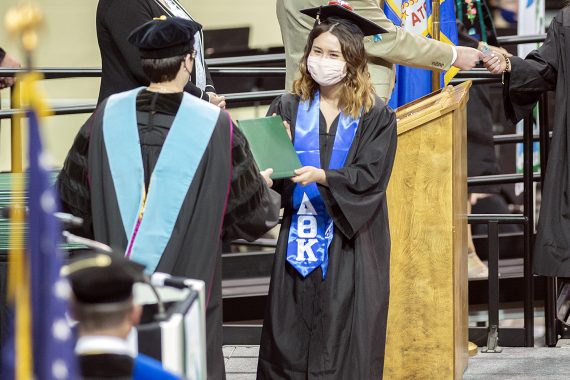 President Faith C. Hensrud confers a diploma