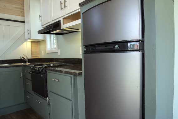 Bemidji State University tiny house Norcold gas/electric refrigerator, full-height kitchen cabinets, granite countertops, Atwood LP gas range and slide-in cooktop.