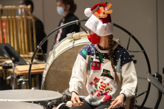 Percussionist Brittney Mollberg wearing a holiday sweater and a reindeer hat