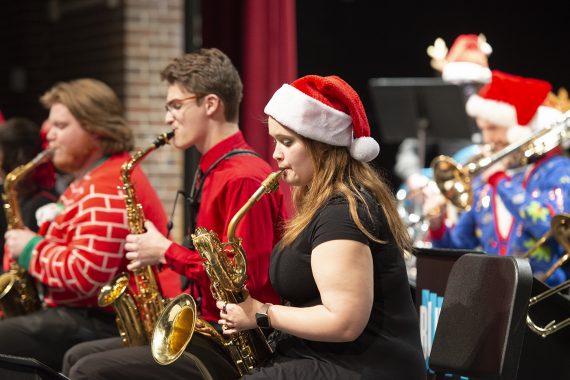 Bemidji State University students wearing holiday apparel and playing the saxophone