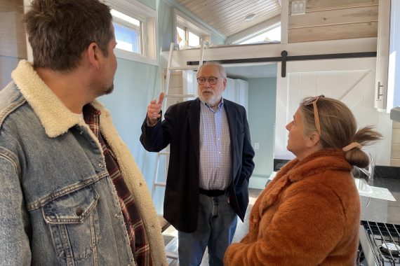 Tim Brockman, professor of technology, art and design, giving Ginny and Chris Kelly a tour of the tiny house