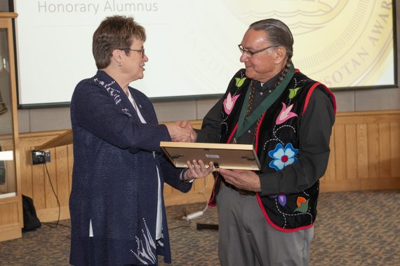 President Faith C. Hensrud presenting Arne Vainio with the 38th Distinguished Minnesotan plaque