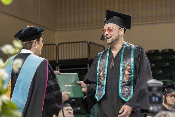 A Bemidji State University graduate receiving a diploma