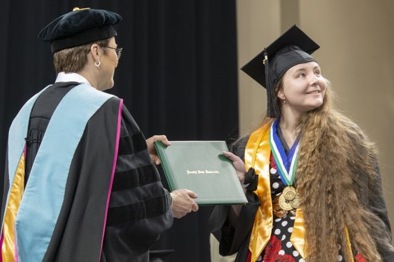 A Bemidji State University graduate receiving a diploma