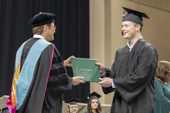 A Bemidji State University graduate receiving a diploma