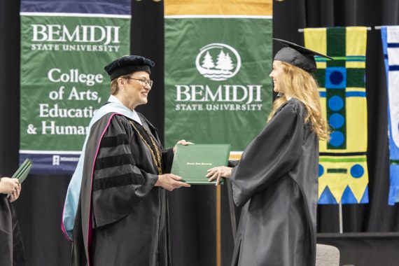 A Bemidji State University graduate receiving a diploma